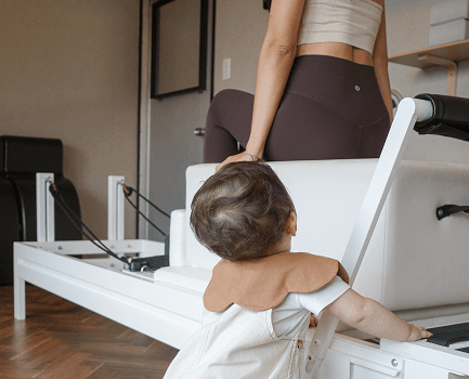 子どもがそばにいるスタジオでピラティスをするインストラクター